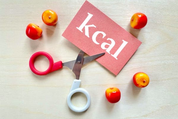 カロリーと書いた紙をハサミでカットしているところ