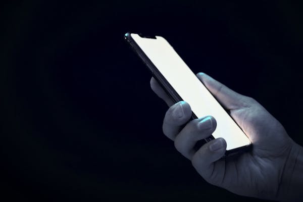 暗闇でスマホを持っている人の手