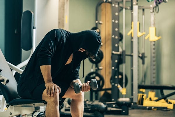 ダンベル運動をしているパーカーを着ている男性