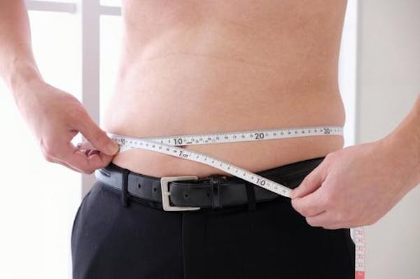 メジャーで腹囲を計測している男性
