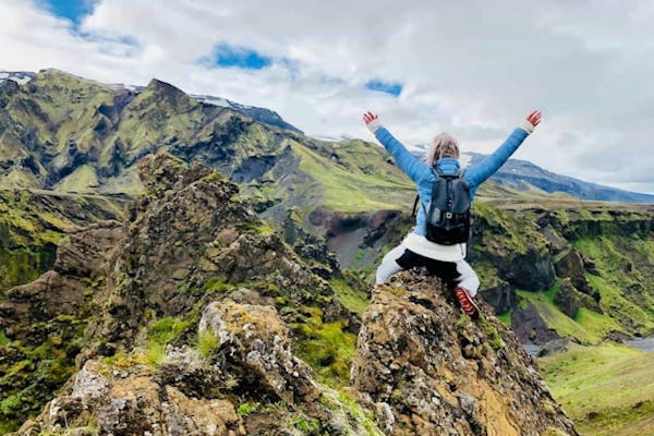 山の岩の上でバンザイをする登山者