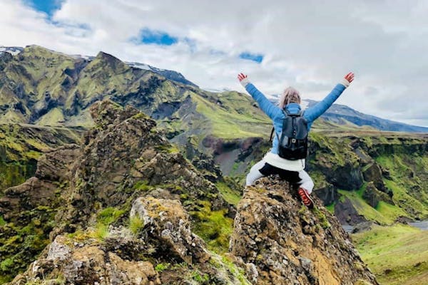 山の岩の上でバンザイをする登山者