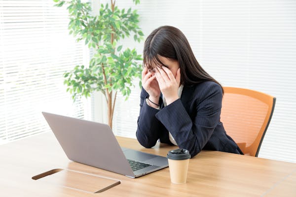 ノートパソコンの前で落ち込むスーツの女性