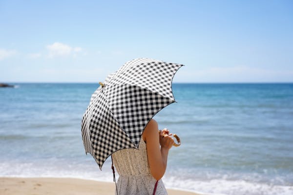 海辺で日傘をさす女性