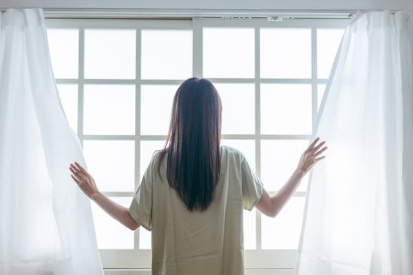 カーテンを開ける女性