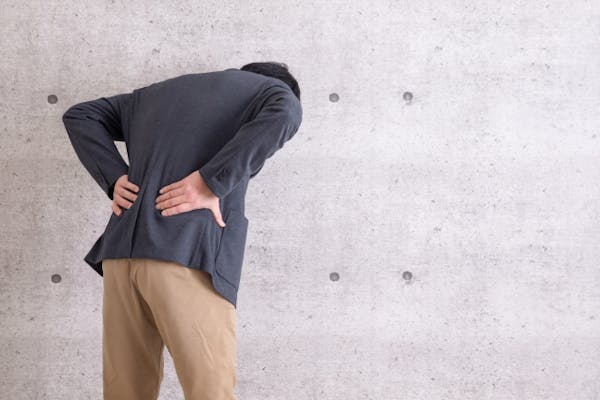 腰をおさえている男性の後ろ姿