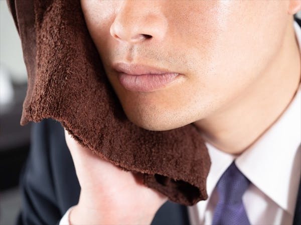 タオルを頬に当てる男性