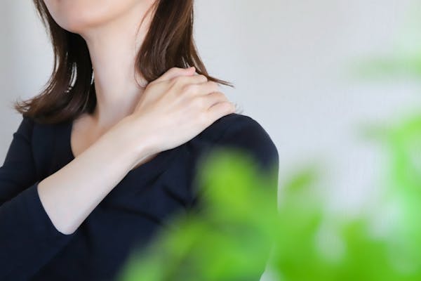 肩に手をあてる女性