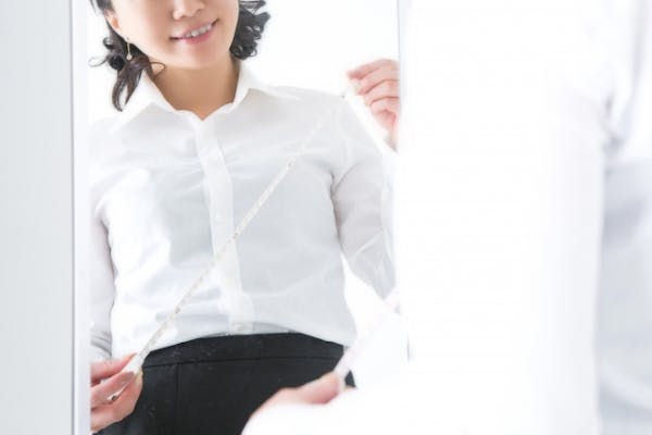 鏡の前でメジャーを引き出している女性