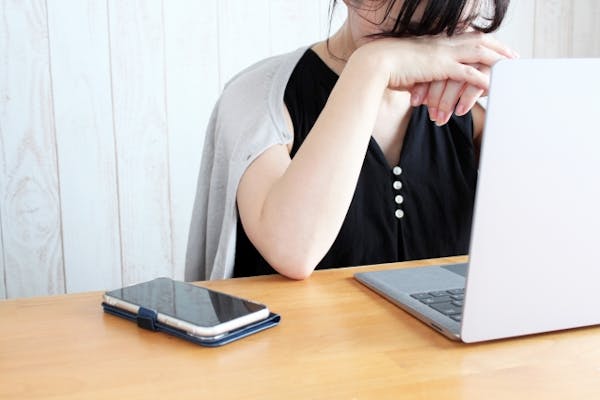 ノートパソコンの前でうなだれる女性
