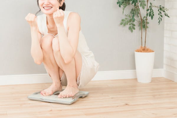体重計に乗ってガッツポーズする女性