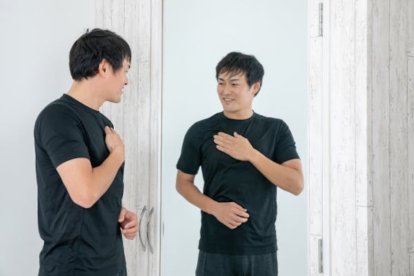 鏡の前の自分の体をチェックする男性