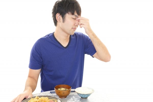 食事の前で目頭をおさえている男性