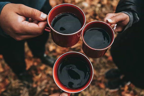 コーヒーのはいったマグカップで乾杯をしているところ