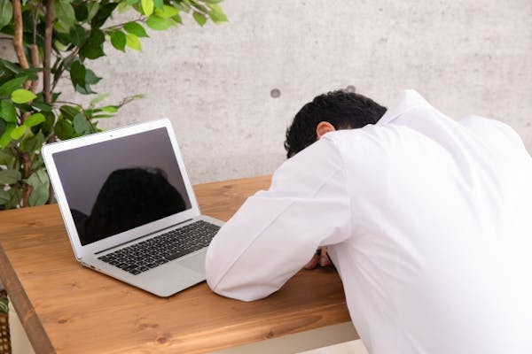 ノートパソコンの前で突っ伏している男性
