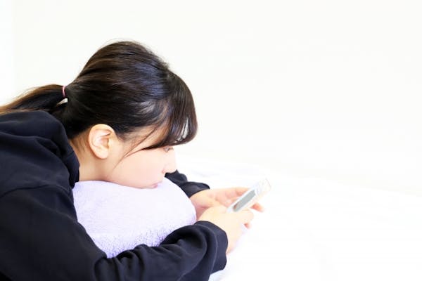 ゴロッとしながらスマホを操作している若い女性