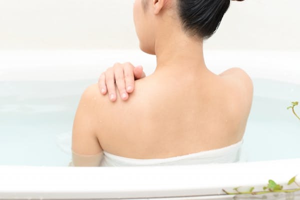 湯船につかる女性の後ろ姿