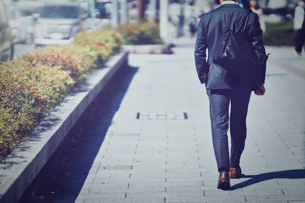 歩いているスーツの男性の後ろ姿