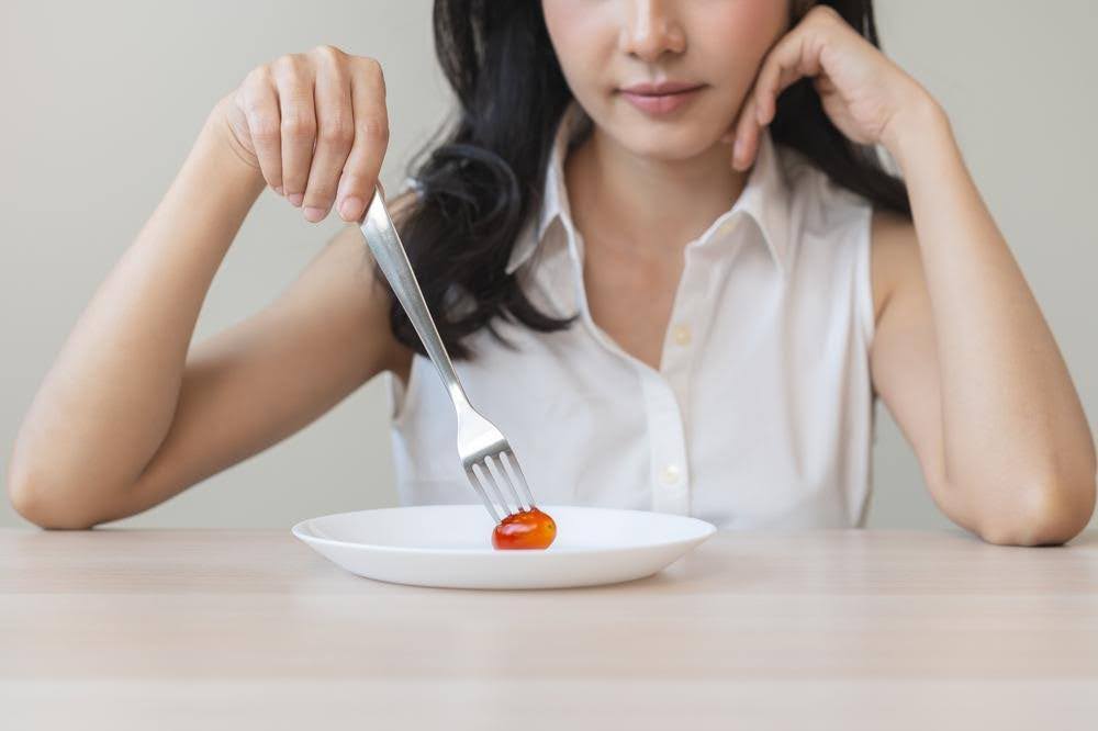 トマトにフォークを刺す女性