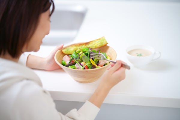 笑顔でサラダを食べている女性