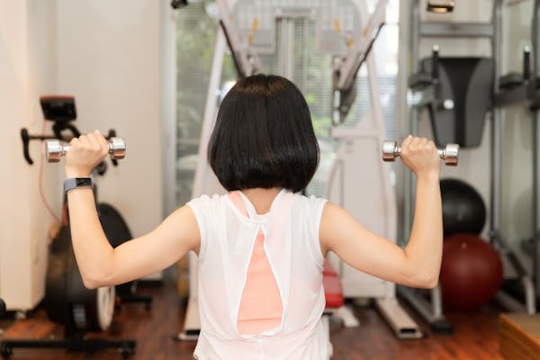ダンベルで運動をしている女性の後ろ姿