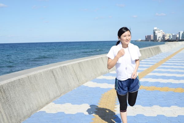 海沿いを走る女性