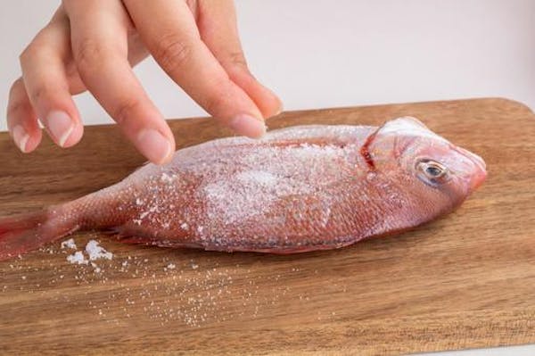 まな板の上の魚に塩をふっているところ