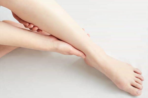 自分の足をマッサージする女性