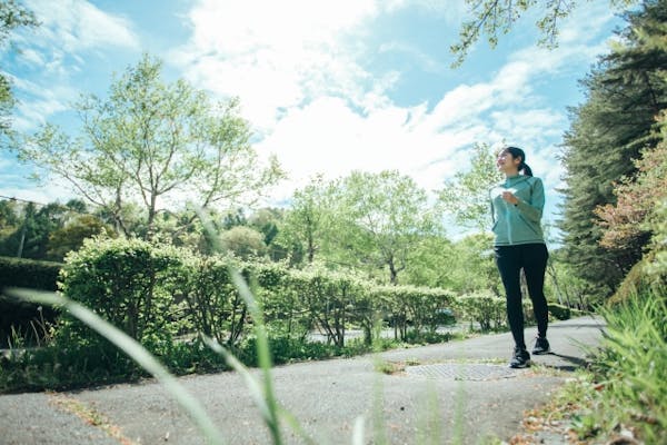 新緑のなかをウォーキングする女性