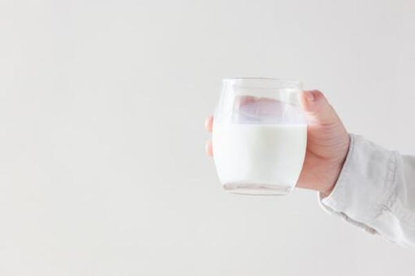 牛乳をはいったグラスを持つ人