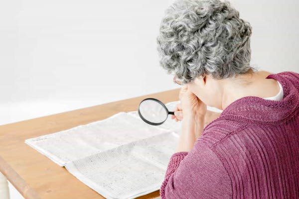 虫眼鏡で地図を見る高齢女性