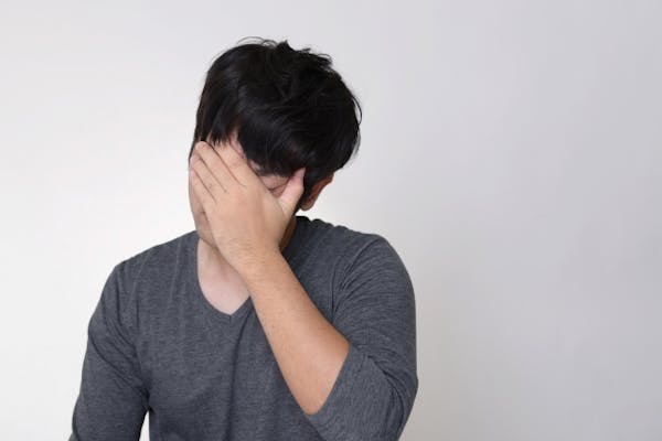 顔に手を当てしんどそうな男性