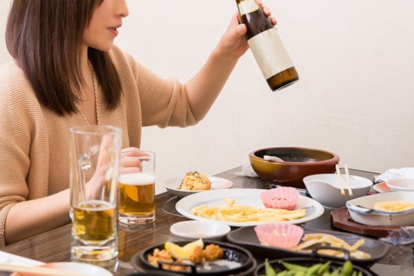 飲み会でお酒の瓶を手に持つ女性