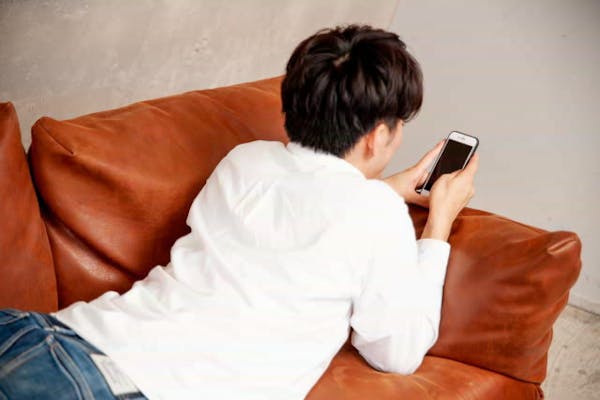 ソファでスマホをみている男性