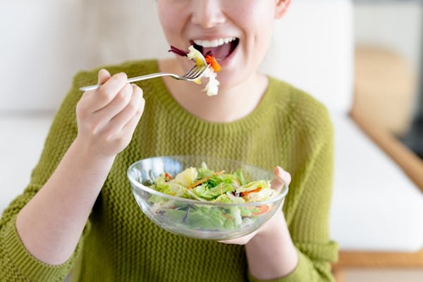 笑顔でサラダを食べている女性