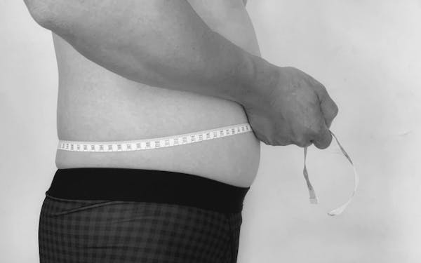 腹囲を測る男性のモノクロ画像