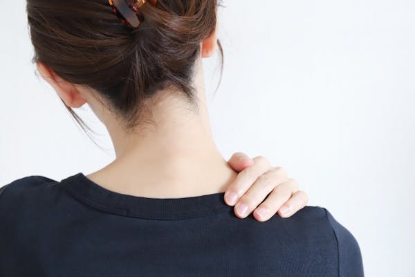 肩にてをあてる女性の後ろ姿