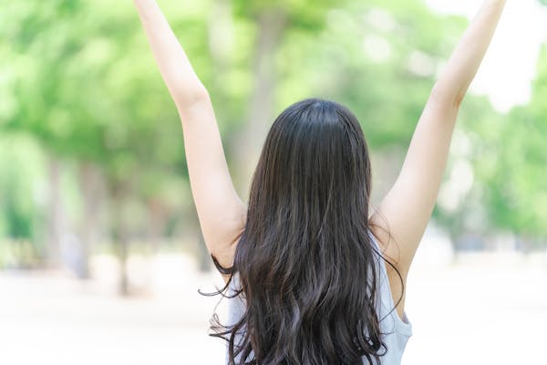 新緑の中で背伸びをする女性の後姿