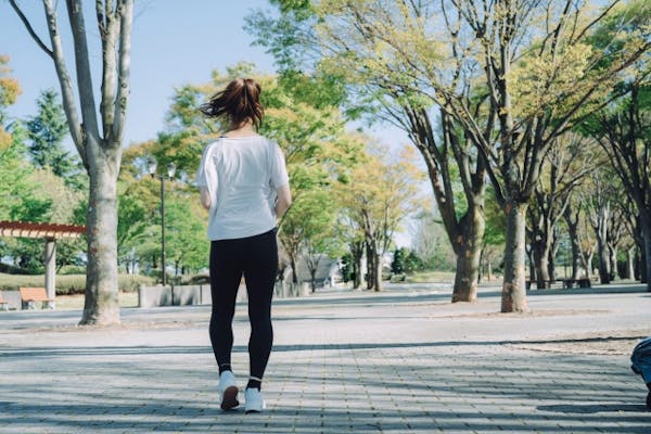 公園をジョギングする女性の後ろ姿