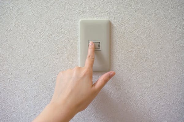 電気のスイッチを押す指