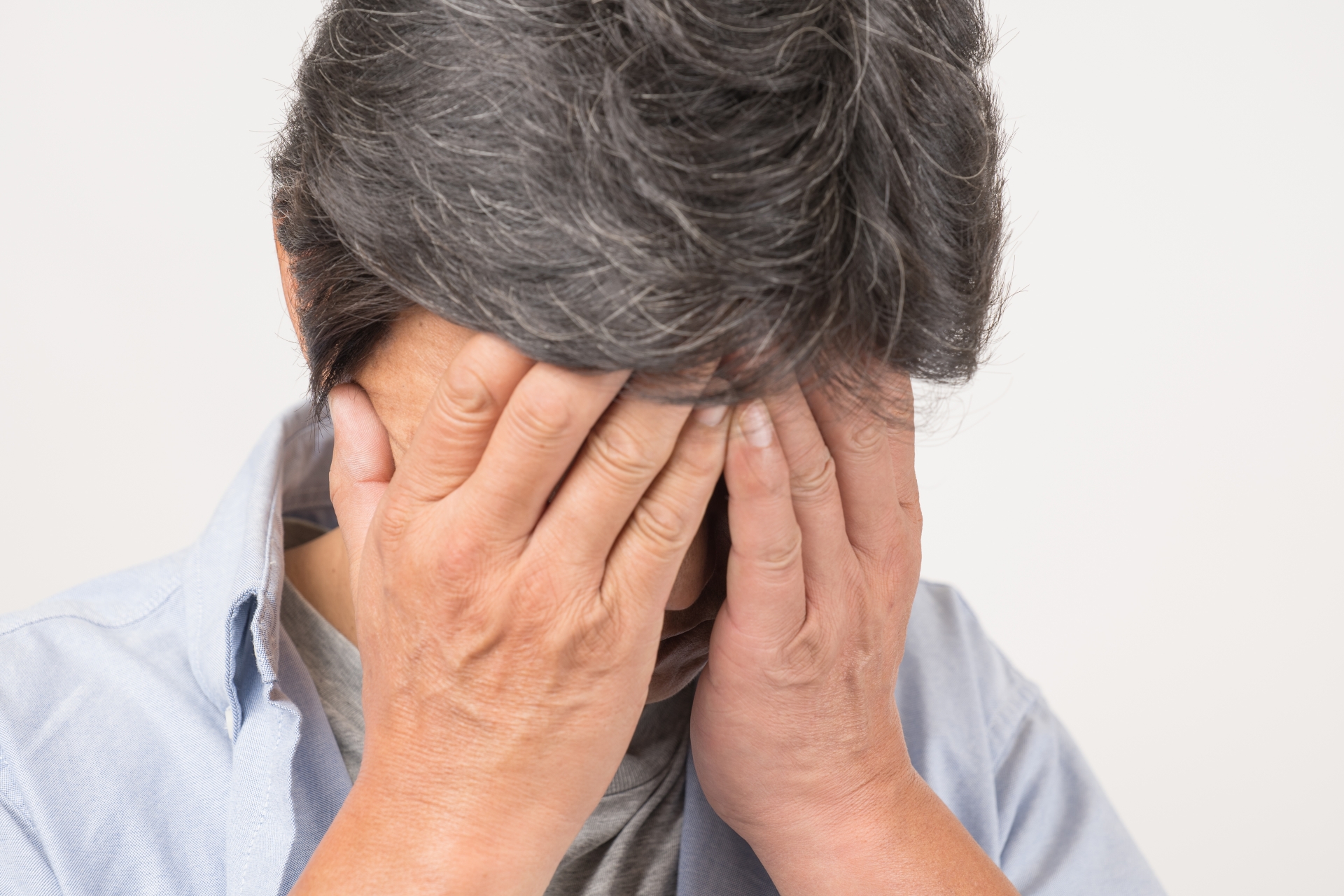 自分の顔を両手で覆う中年男性