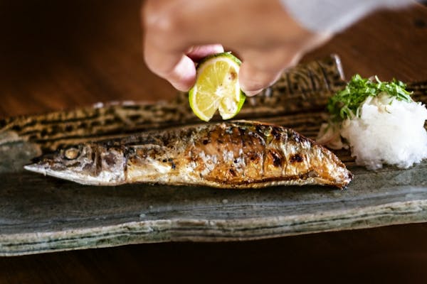 焼いたサンマにすだちをかけているところ