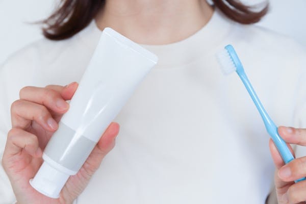 歯磨き粉と歯ブラシを持っている女性