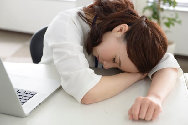 ノートパソコンの前で寝ている女性