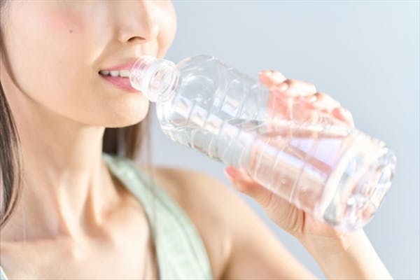 ペットボトルから水を飲む女性