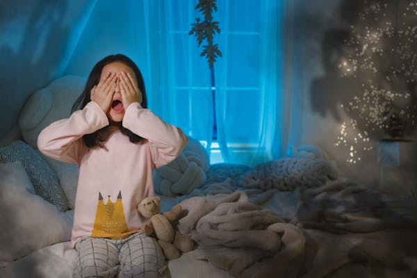 ベッドの上で両目を覆っている女の子