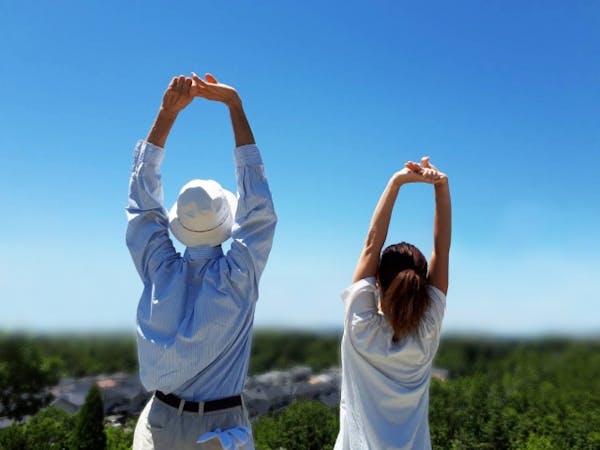 青空の下背伸びをする男女
