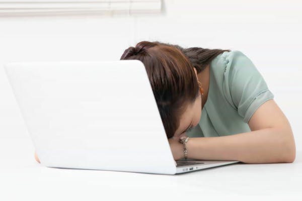 ノートパソコンの前で突っ伏している女性