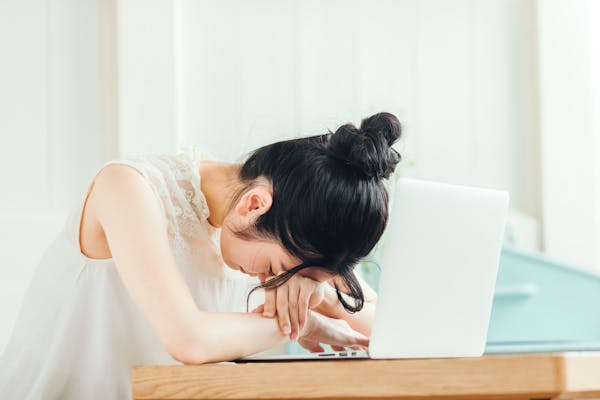 ノートパソコンの上に突っ伏している女性