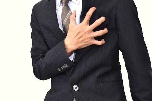 心臓をおさえるスーツの男性